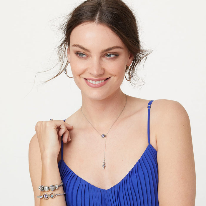 Model wearing a Brighton silver-plated Y-necklace with purple crystal drops and coordinating Brighton accessories