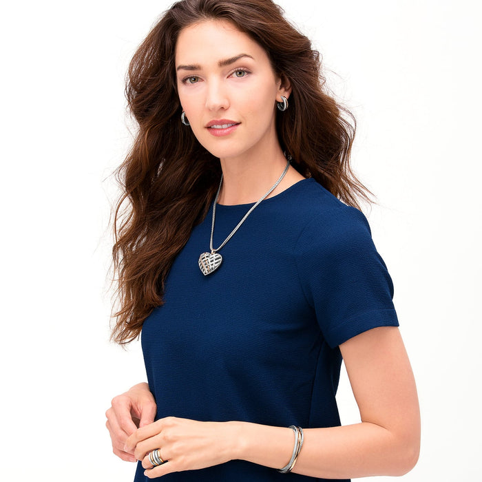 Model wearing a Brighton silver-tone heart pendant necklace with coordinating Brighton hoop earrings and bangle bracelets