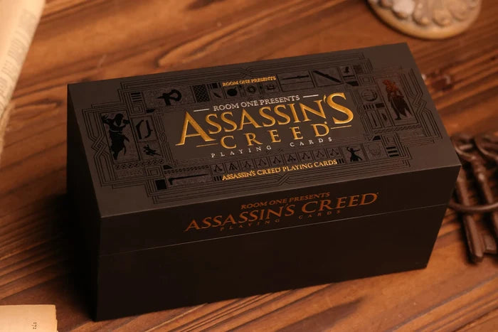 A close-up of the Assassin's Creed Legacy playing cards Half Brick box set, featuring the title and some intricate designs related to the Assassin's Creed series.