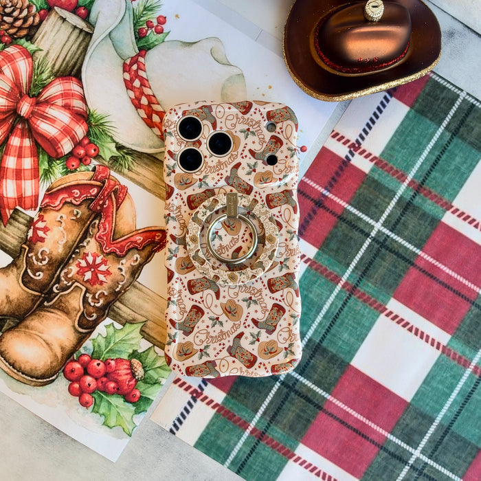 Close-up of the Boot Scootin' Christmas MagSafe grip ring on the matching cowboy boot iPhone case, on red and green plaid