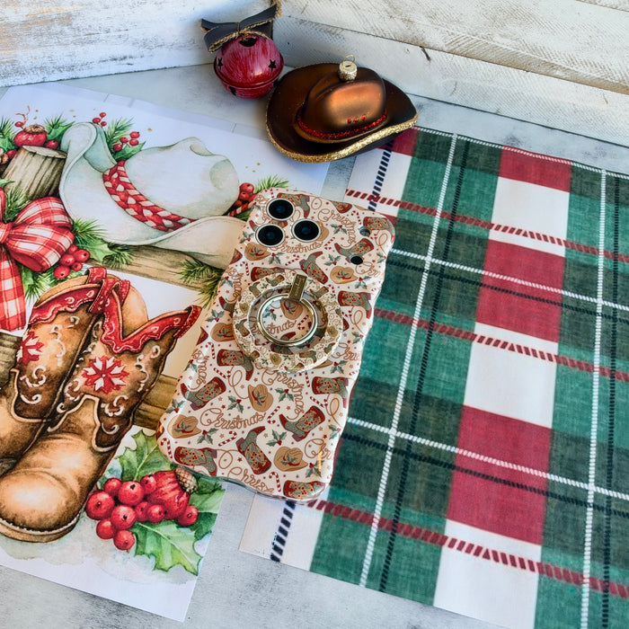 Boot Scootin' Christmas iPhone case with the matching grip ring snapped on, on red and green plaid with a cowboy hat ornament and jingle bell