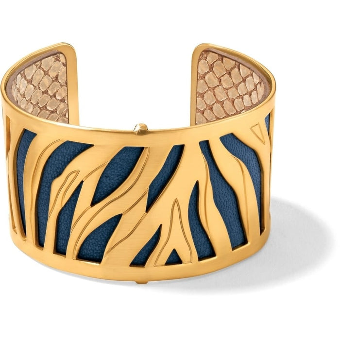 Brighton gold-plated cuff bracelet with cutout tiger stripe design over blue and snake-print leather on a white background