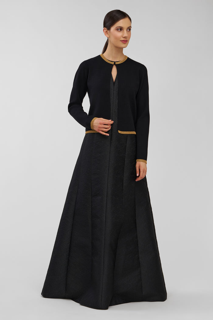 Woman wearing a black gown with a fitted cardigan on a white background