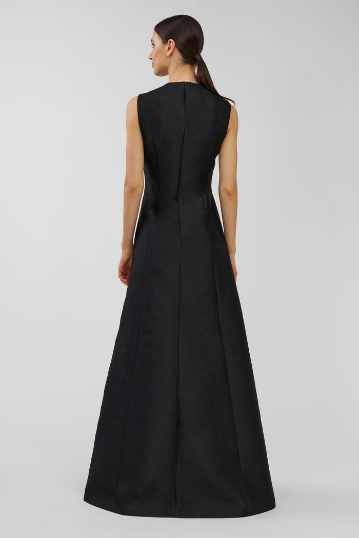 Woman wearing a black sleeveless gown on a light gray background