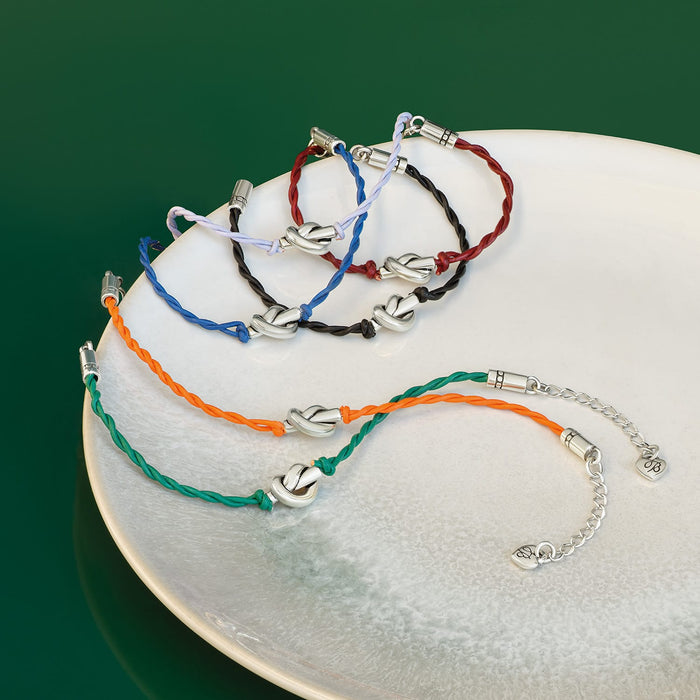 Brighton leather cord bracelets in assorted colors with silver-plated knot accents styled on a ceramic dish