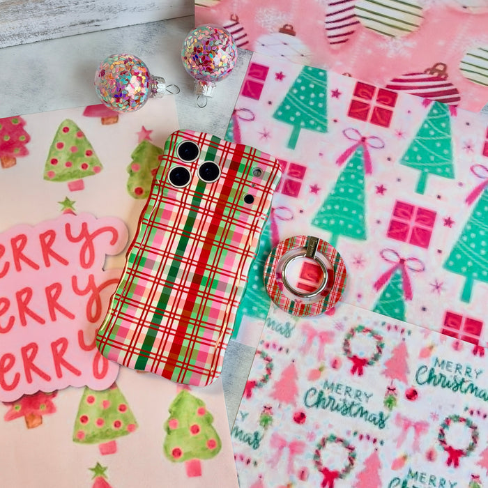 Merry Little Plaid iPhone case with the matching plaid grip ring set beside it, with a pink Merry sign and glitter ornaments