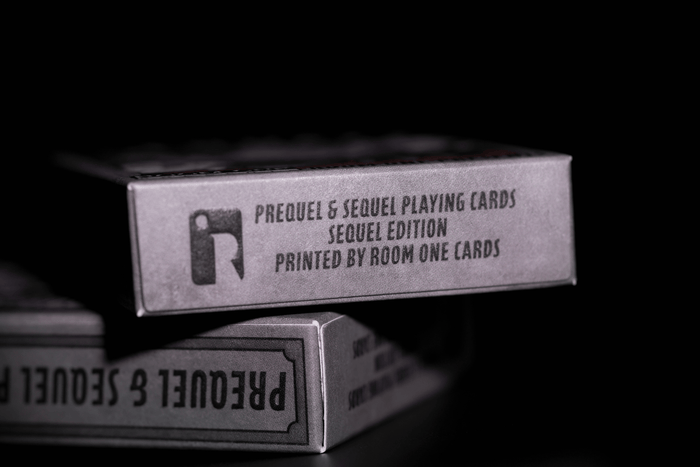 Stack of 'Prequel & Sequel Playing Cards' boxes with text on a dark background