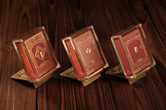 Three decks of cards with gold and red design on a brown textured background