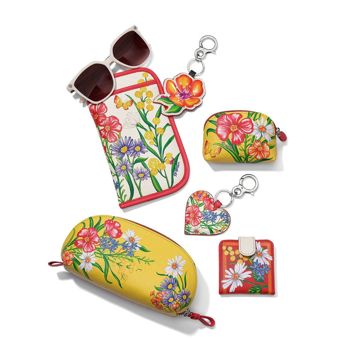 Brighton sunglasses case styled with floral-print pouch, coin purse, heart key fob, and other accessories on white background